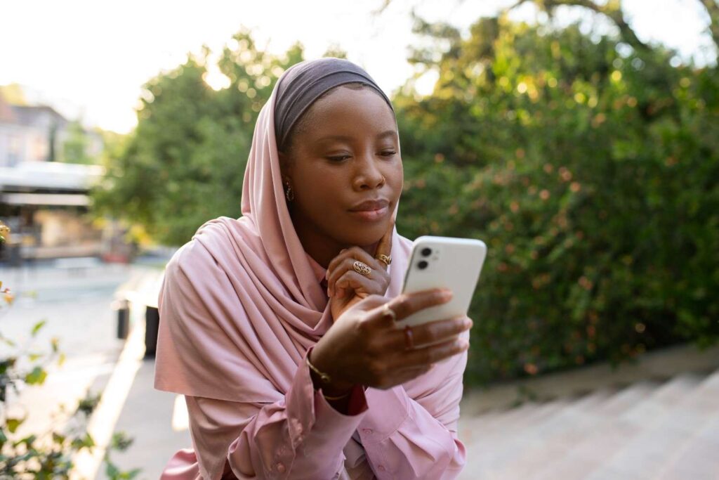 Nigerian woman in traditional outfit analyzing blockchain data on smartphone (investment for nigerian youth)