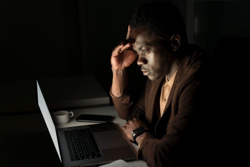 African youth entrepreneur working on laptop in market setting