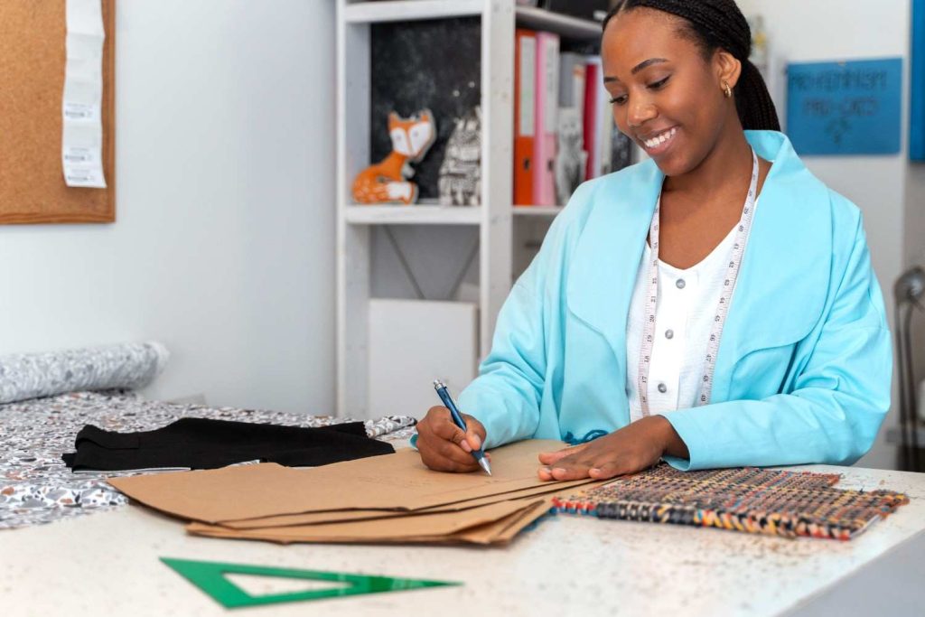Sarah, an African youth entrepreneur, fits a dress in her cozy Nigerian fashion shop.