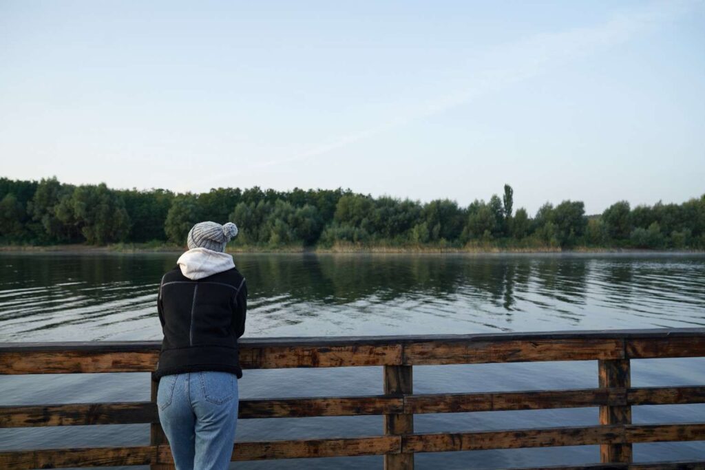 Young Nigerian reflecting to discover their purpose by a serene lake.