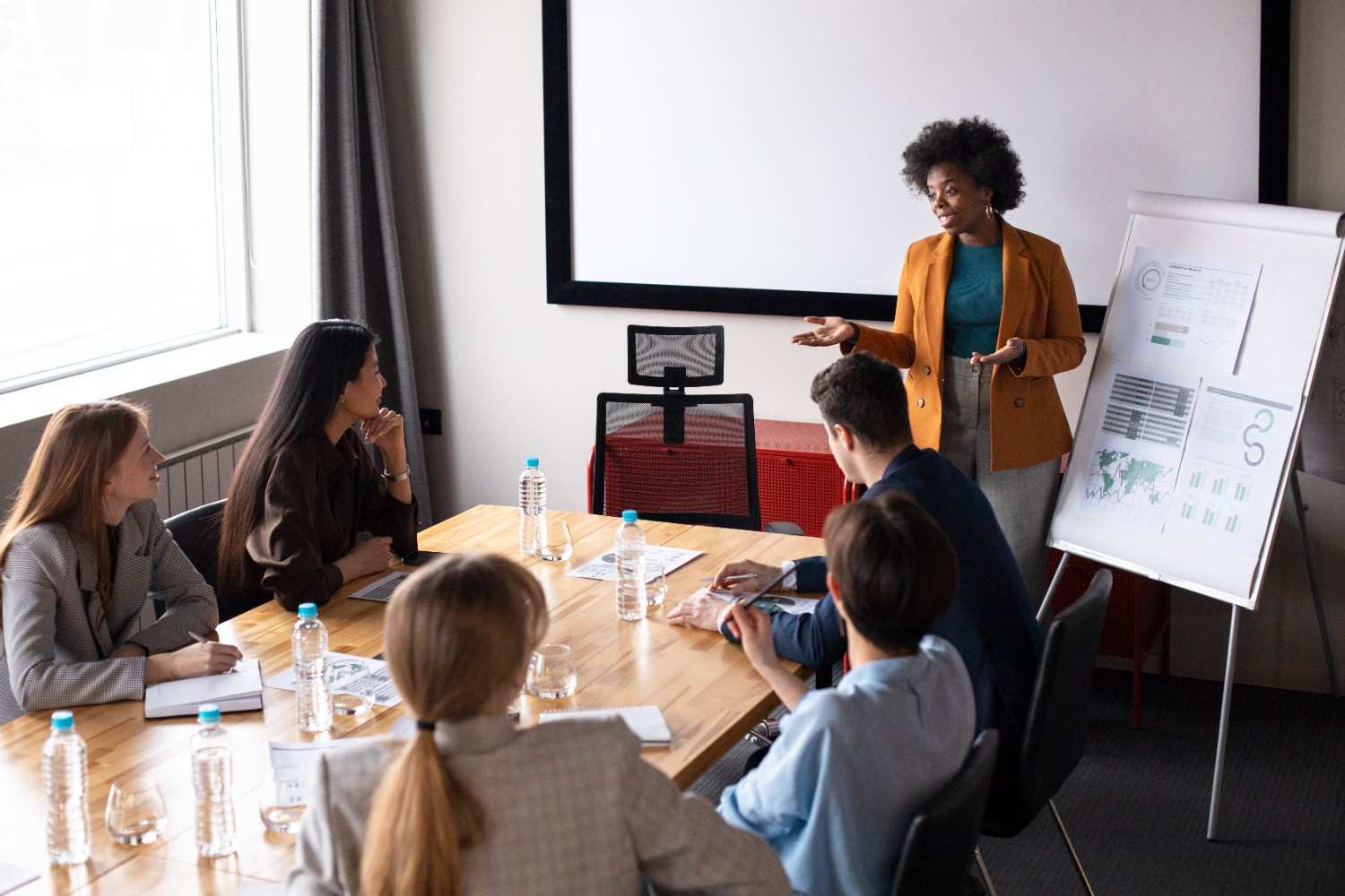 Young adult reviewing community project plans surrounded by diverse team members