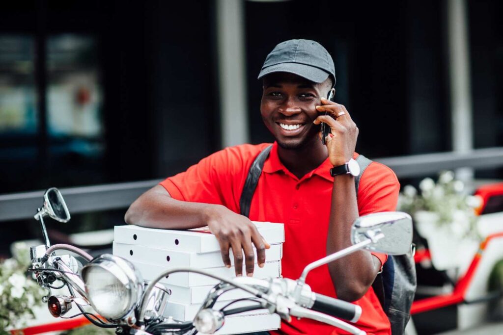 Nigerian motorcycle delivery rider using smartphone app to manage orders