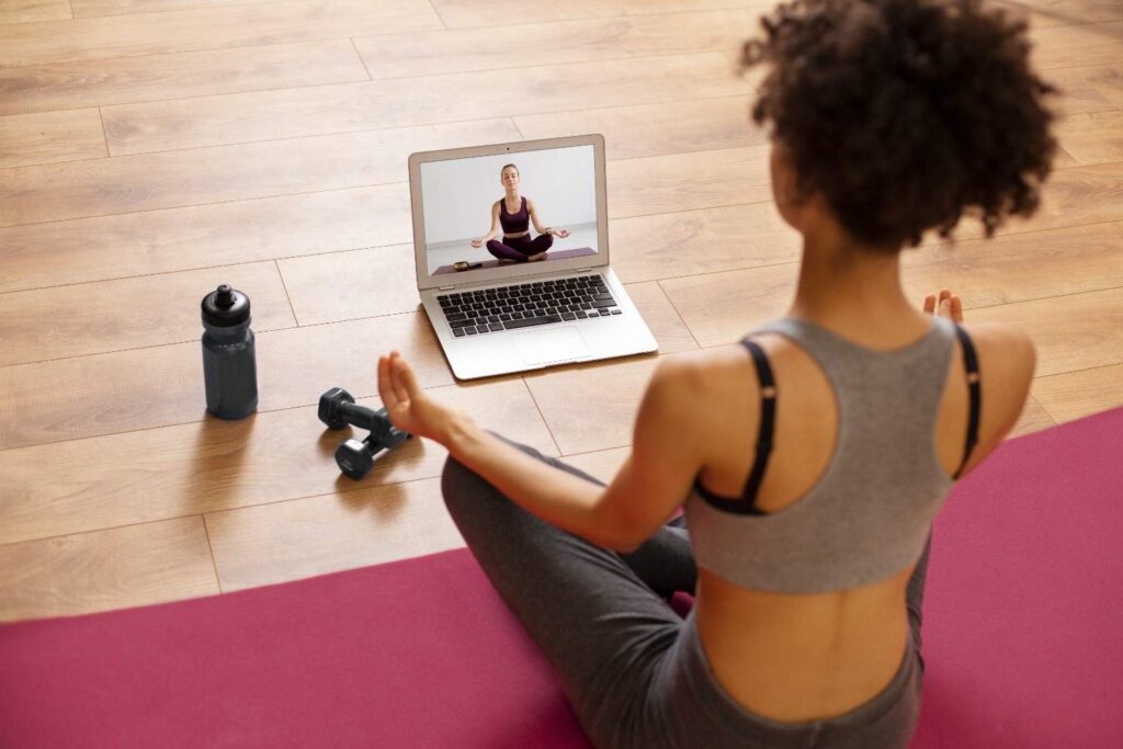 Fitness trainer leading virtual workout session from home gym using laptop