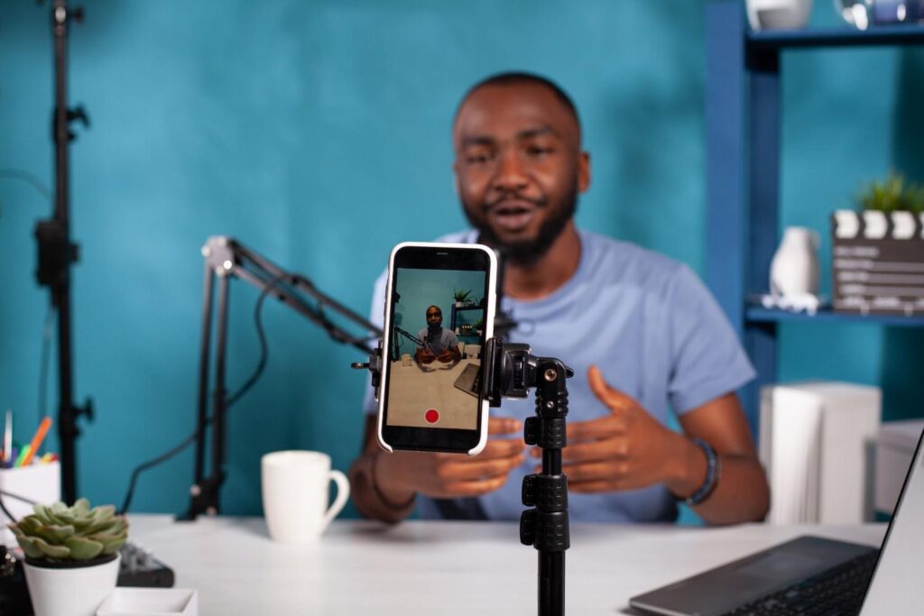 Nigerian content creator filming with smartphone and ring light at home