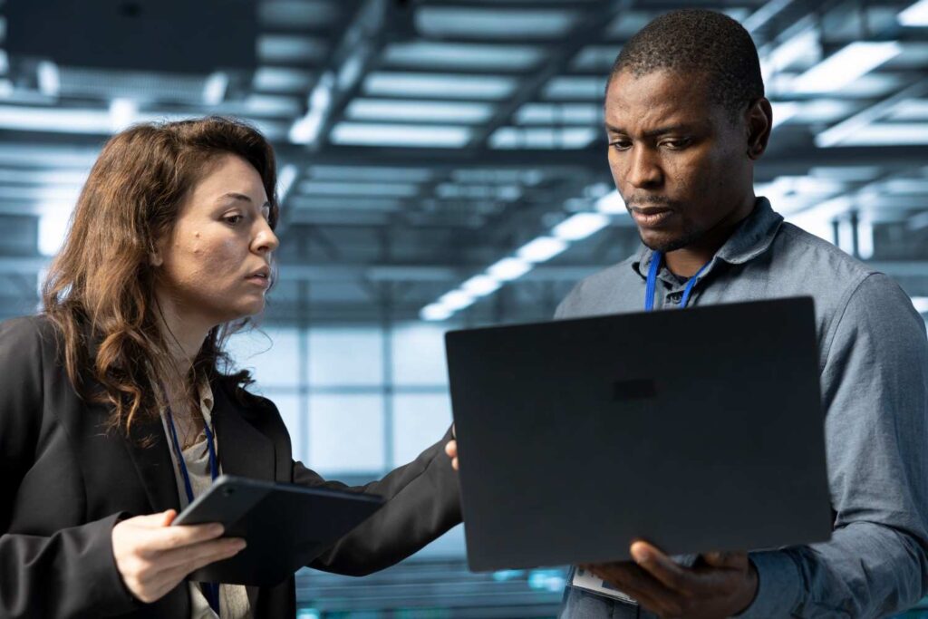 Technician repairing laptop while explaining issue to client