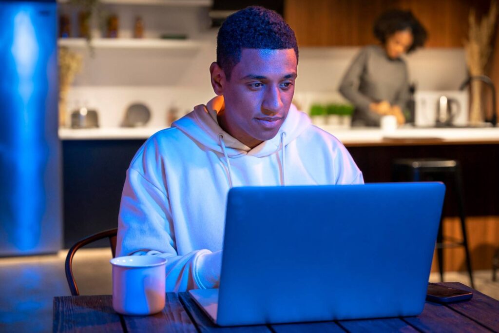 Nigerian youth coding on laptop with Google logo in background.